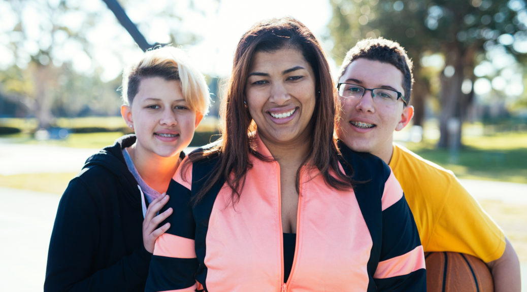 Latina mother with two teenage children playing basketball